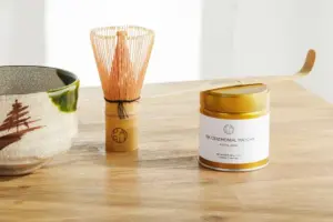 PARU 10K Ceremonial Matcha tin beside a bamboo whisk, tea scoop, and ceramic bowl