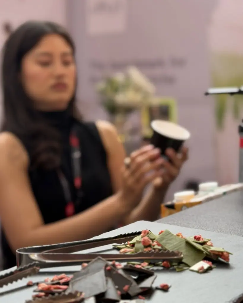 Broken green and dark chocolate pieces with pink crumbs and serving tongs
