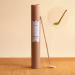 Anatae bamboo chashaku leaning against its labeled cardboard tube, with inset showing spoon holding matcha