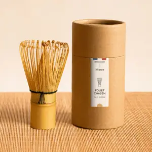 Anatae bamboo matcha chasen beside labeled cylindrical container on bamboo mat