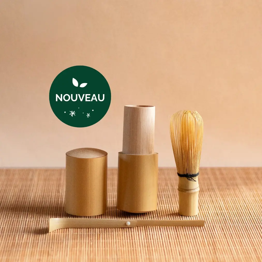 Mini bamboo matcha whisk, scoop, and cylindrical travel case on a bamboo mat