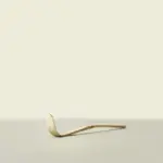 Curved bamboo matcha scoop resting on a light surface