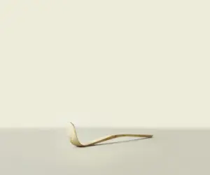 Curved bamboo matcha scoop resting on a light surface
