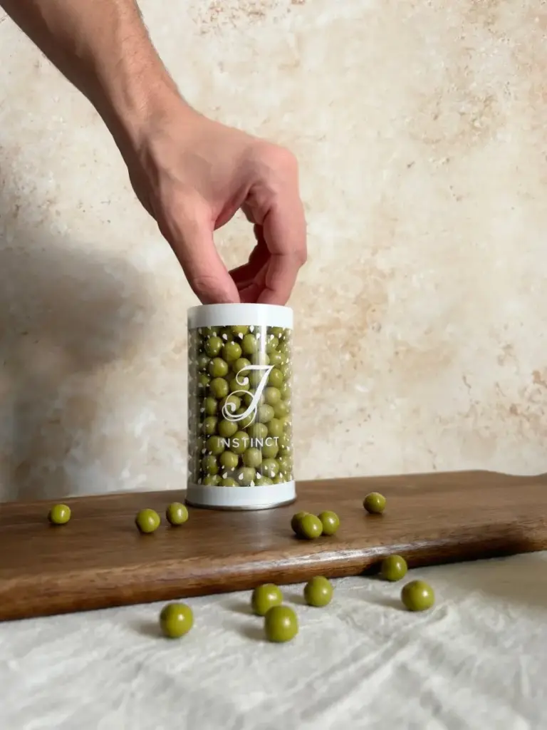 Hand reaching into a clear Instinct container filled with green matcha-coated balls
