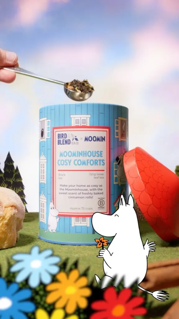 Spoonful of loose tea above a blue Moominhouse Cosy Comforts tin with a red roof lid and Moomin character