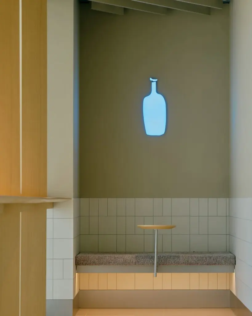 Tiled seating nook beneath a glowing blue bottle logo