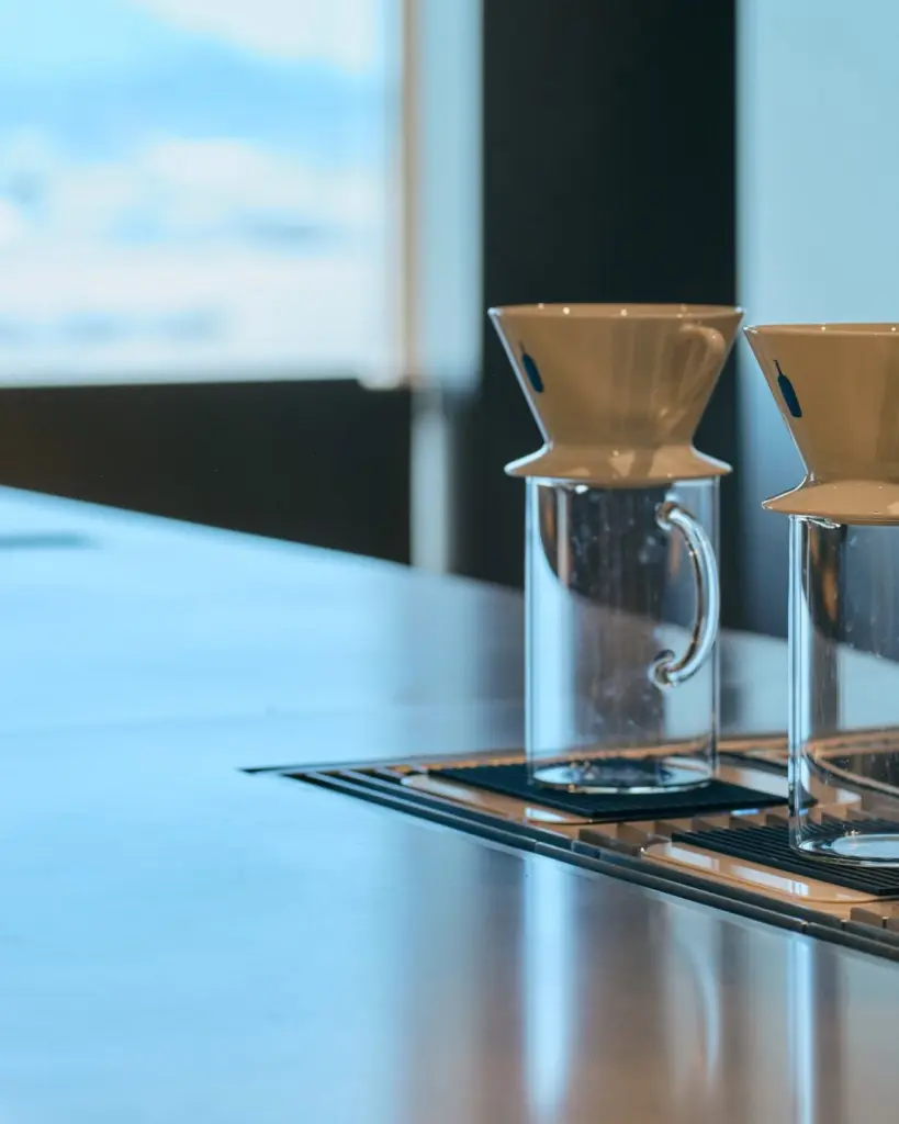 White ceramic pour-over drippers resting on clear glass pitchers