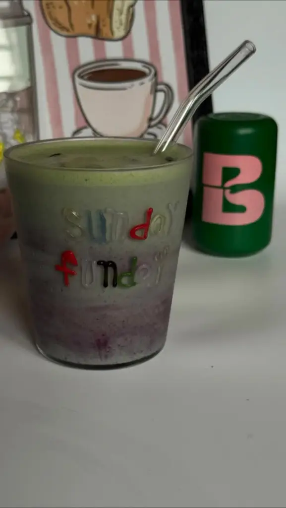 Layered green and purple iced drink in a Sunday Funday glass with a metal straw