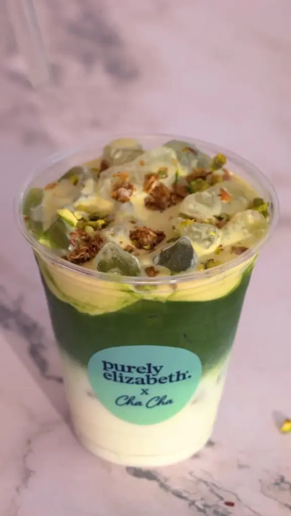 Layered green iced drink with pale topping and scattered crunchy pieces