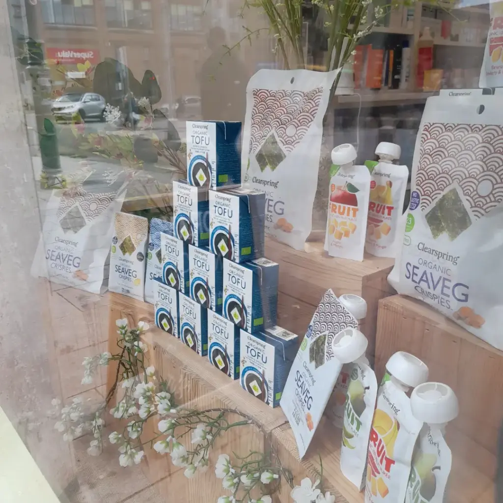 Tofu cartons, sea vegetable crispies, and fruit pouches arranged in a shop window