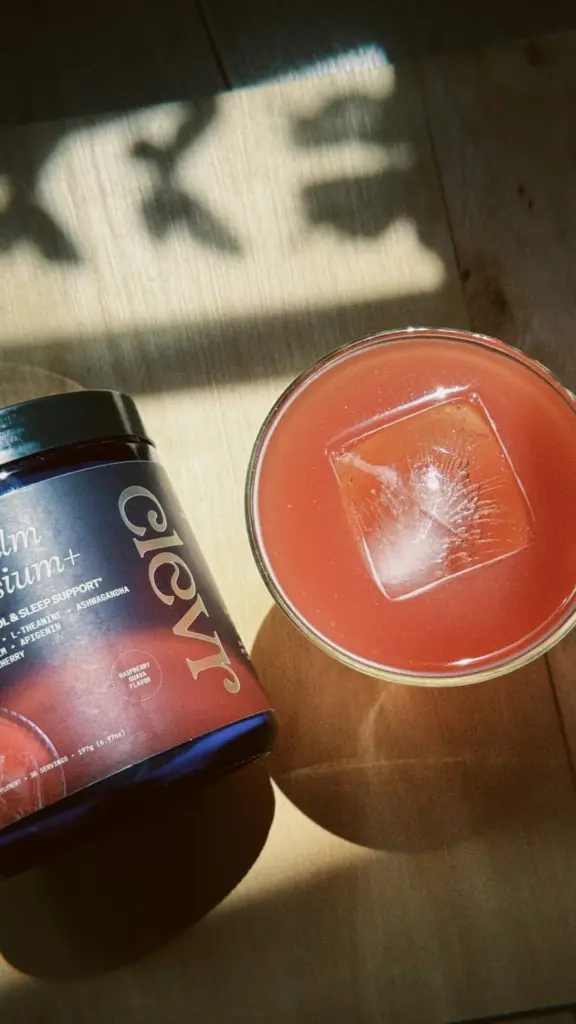 Clevr Calm Magnesium+ container beside a pink drink with a square ice cube