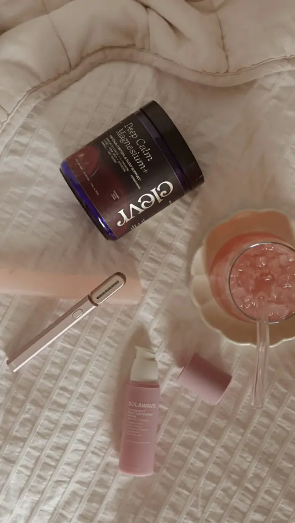 Clevr Deep Calm Magnesium+ jar beside a pink drink and skincare tools on a quilt