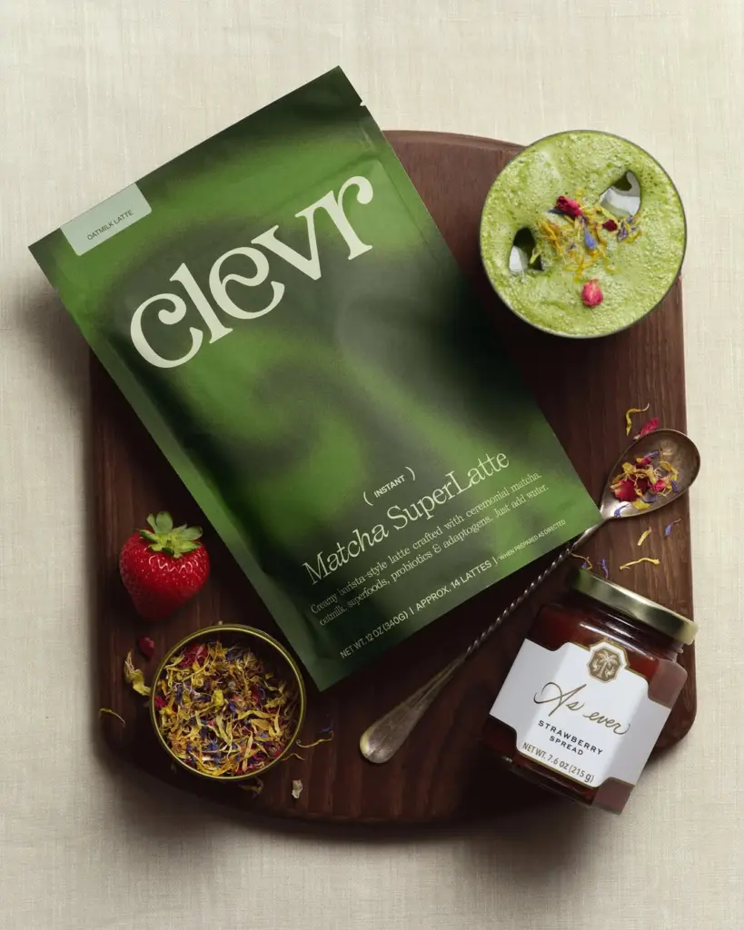 Clevr Matcha SuperLatte pouch beside a green iced drink, strawberry spread, fresh strawberry, and dried flowers