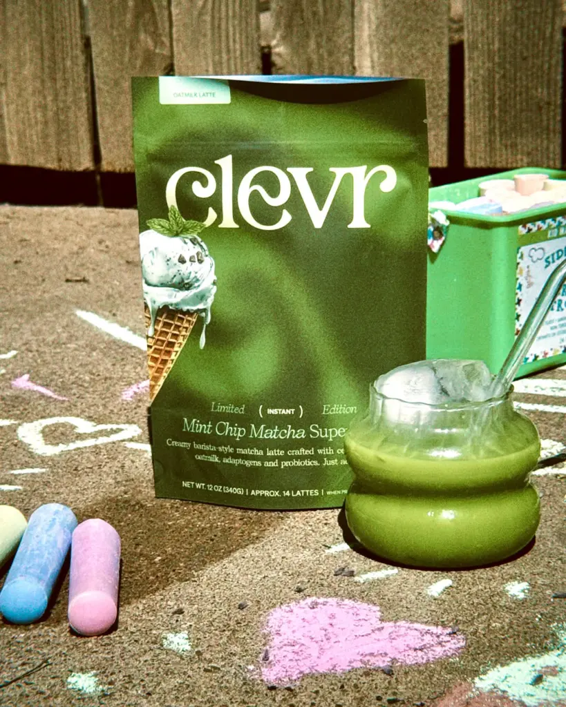 Clevr Mint Chip Matcha SuperLatte pouch beside a glass of green iced latte and pastel chalk