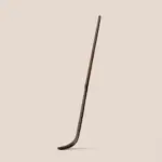 Long dark brown bamboo matcha scoop with a curved tip on a beige background