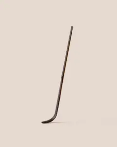 Long dark brown bamboo matcha scoop with a curved tip on a beige background