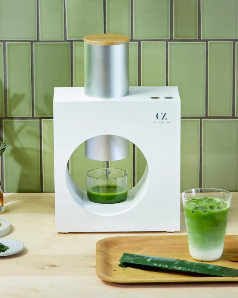 White Cuzen Matcha machine beside a layered iced green drink