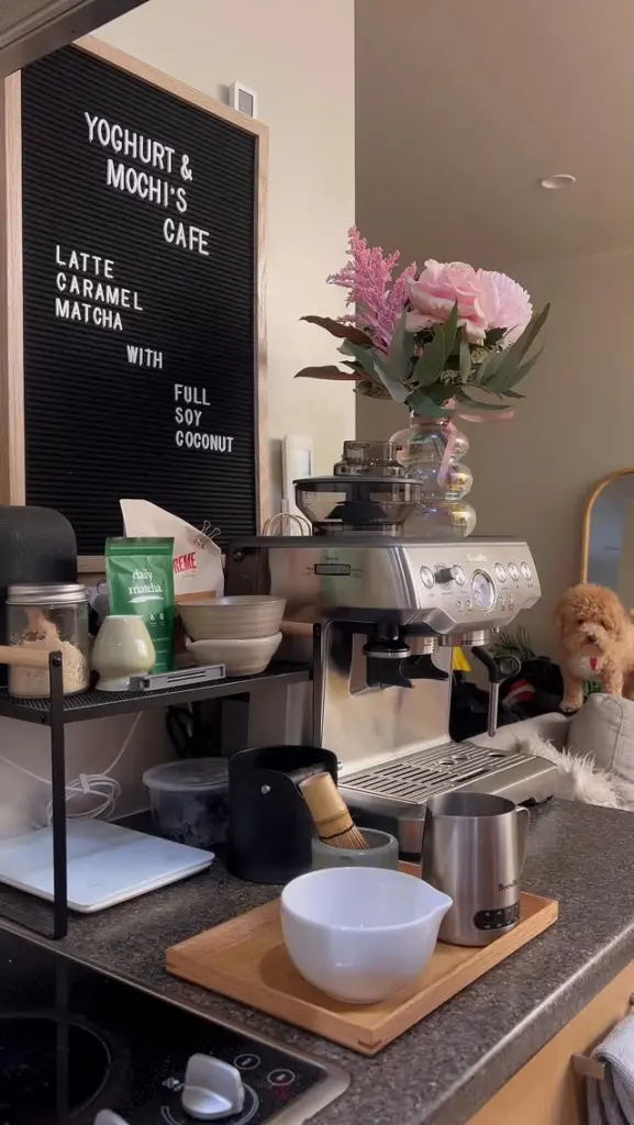 Cafe counter with an espresso machine, matcha pouch, whisk, bowl, and milk frother