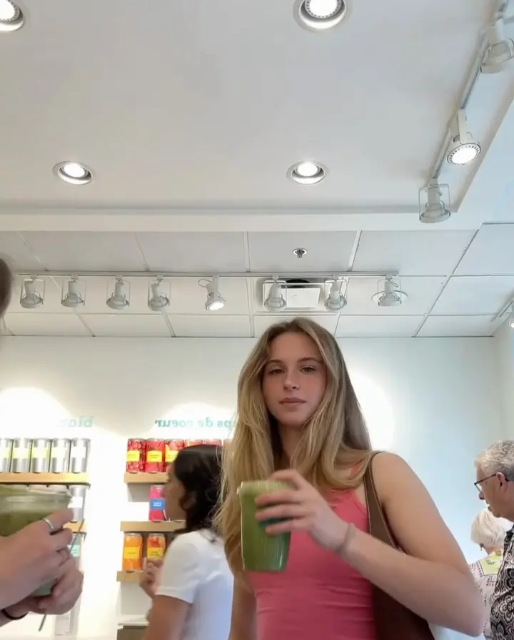 Shopper holding a clear cup filled with a green iced drink
