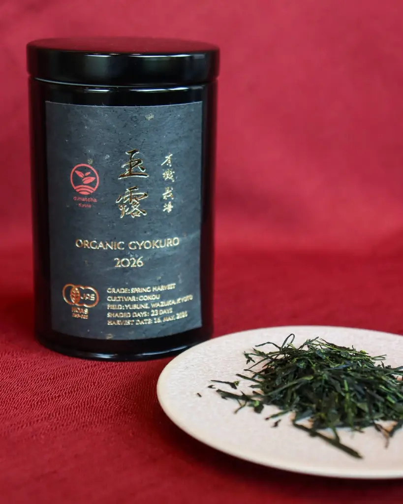 Black d:matcha Kyoto Organic Gyokuro tin beside loose tea leaves on a plate