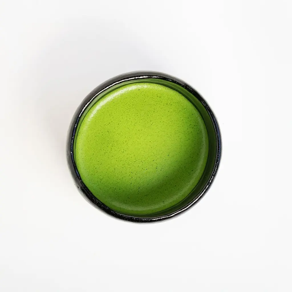 Top view of bright green matcha in a round black bowl