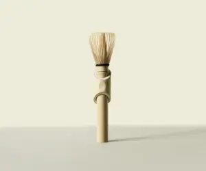 Full-length bamboo matcha whisk standing upright against a pale background