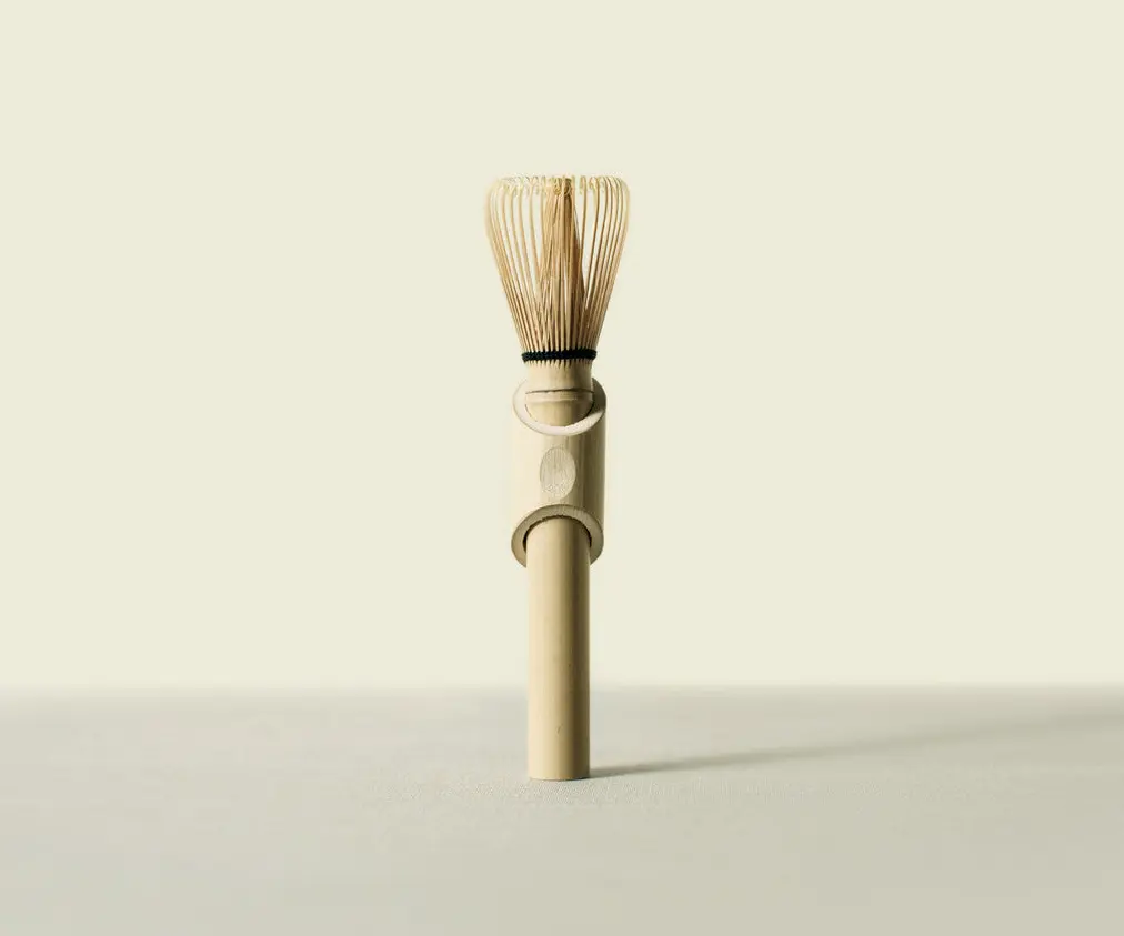 Full-length bamboo matcha whisk standing upright in a fitted holder