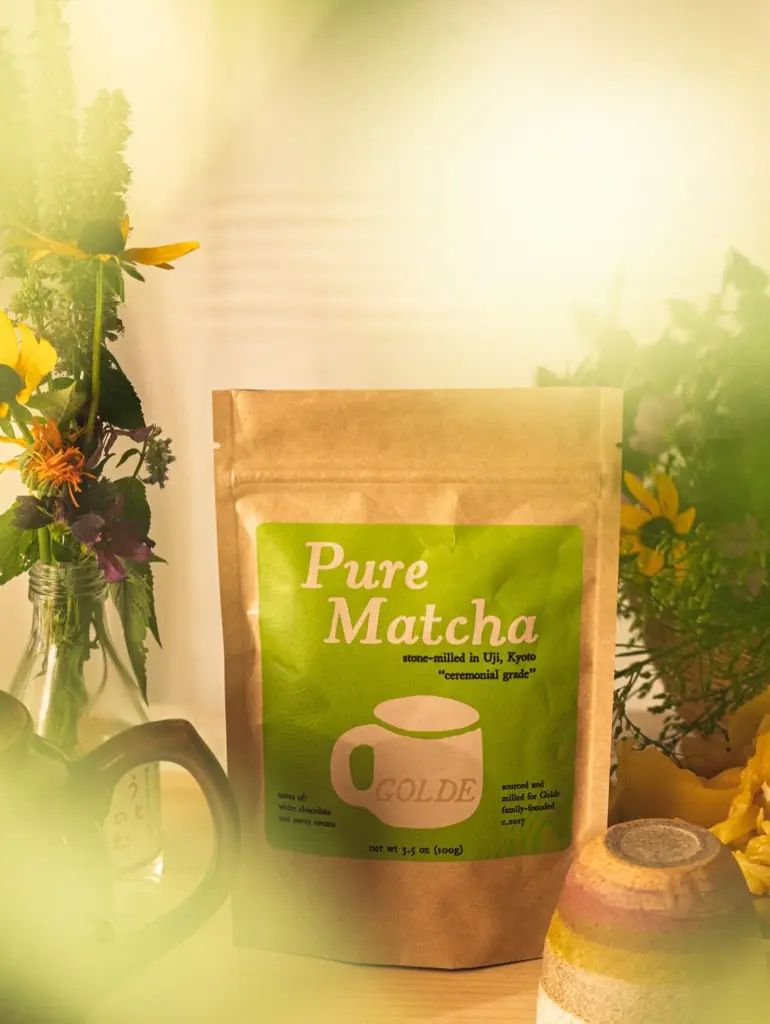 Golde Pure Matcha pouch surrounded by flowers in golden sunlight