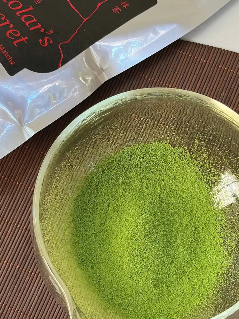 Bright green matcha powder in a clear glass bowl