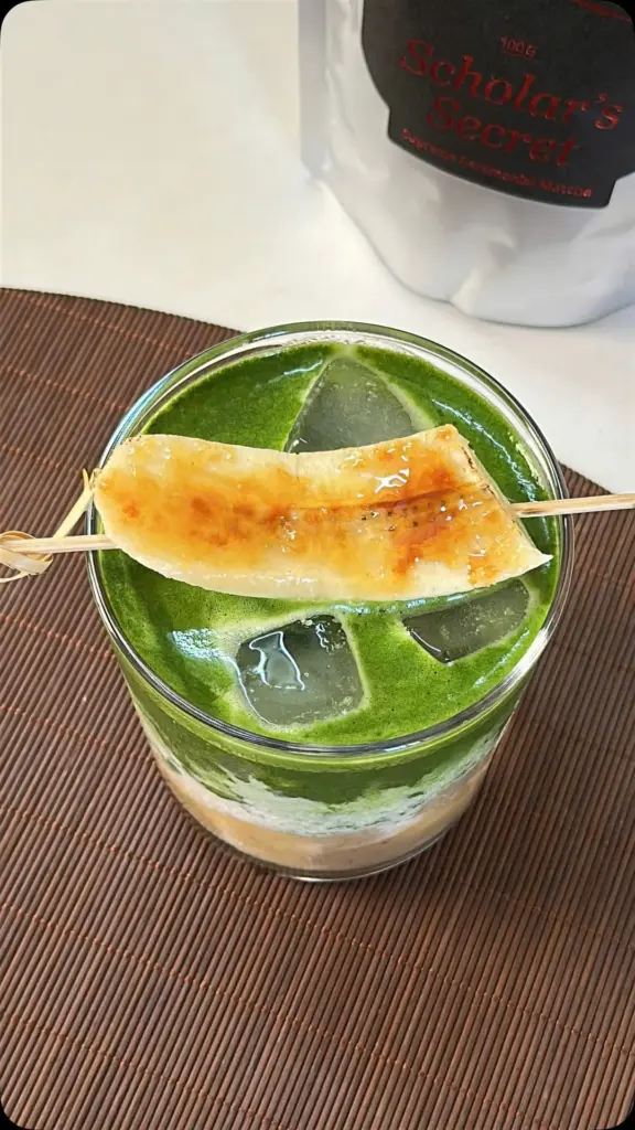 Layered iced matcha drink topped with a skewered caramelized banana slice