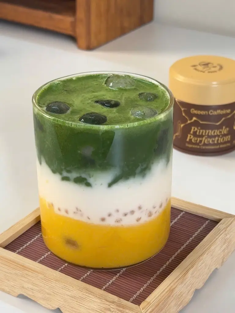 Layered yellow, white, and green iced drink in a clear glass