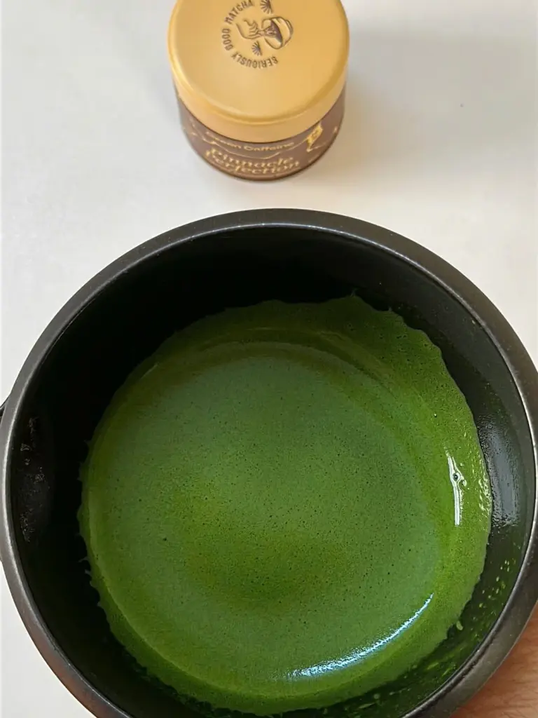 Bright green whisked matcha in a black bowl