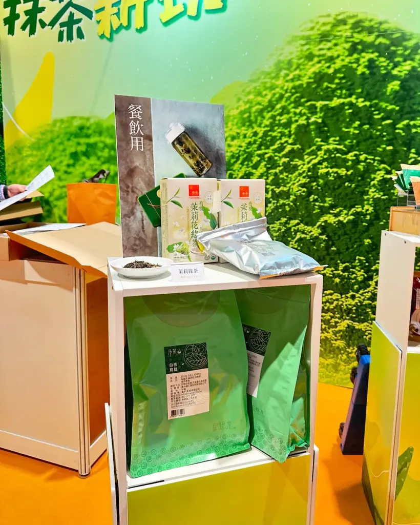 Jasmine green tea boxes, loose leaves, and large green bags on a display shelf