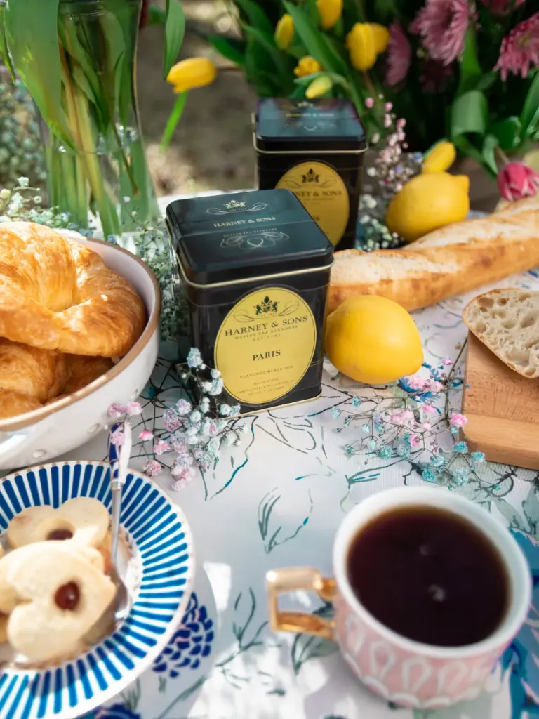 Harney & Sons Paris tea tins among tea, pastries, bread, lemons, and flowers