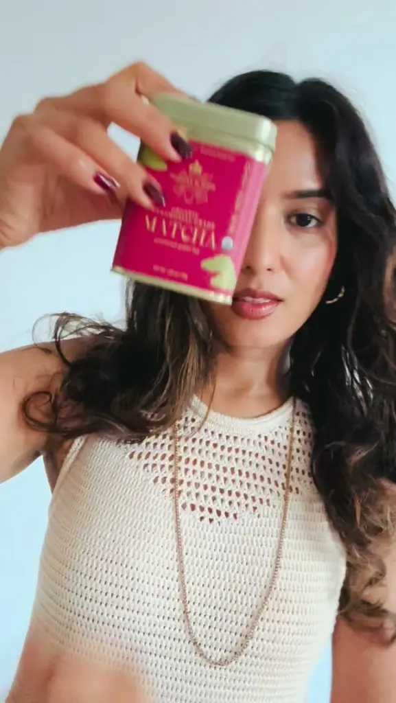 Woman holding a pink Harney & Sons tea tin near her face