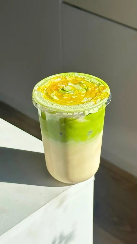 Layered green matcha latte with ice in a clear takeaway cup