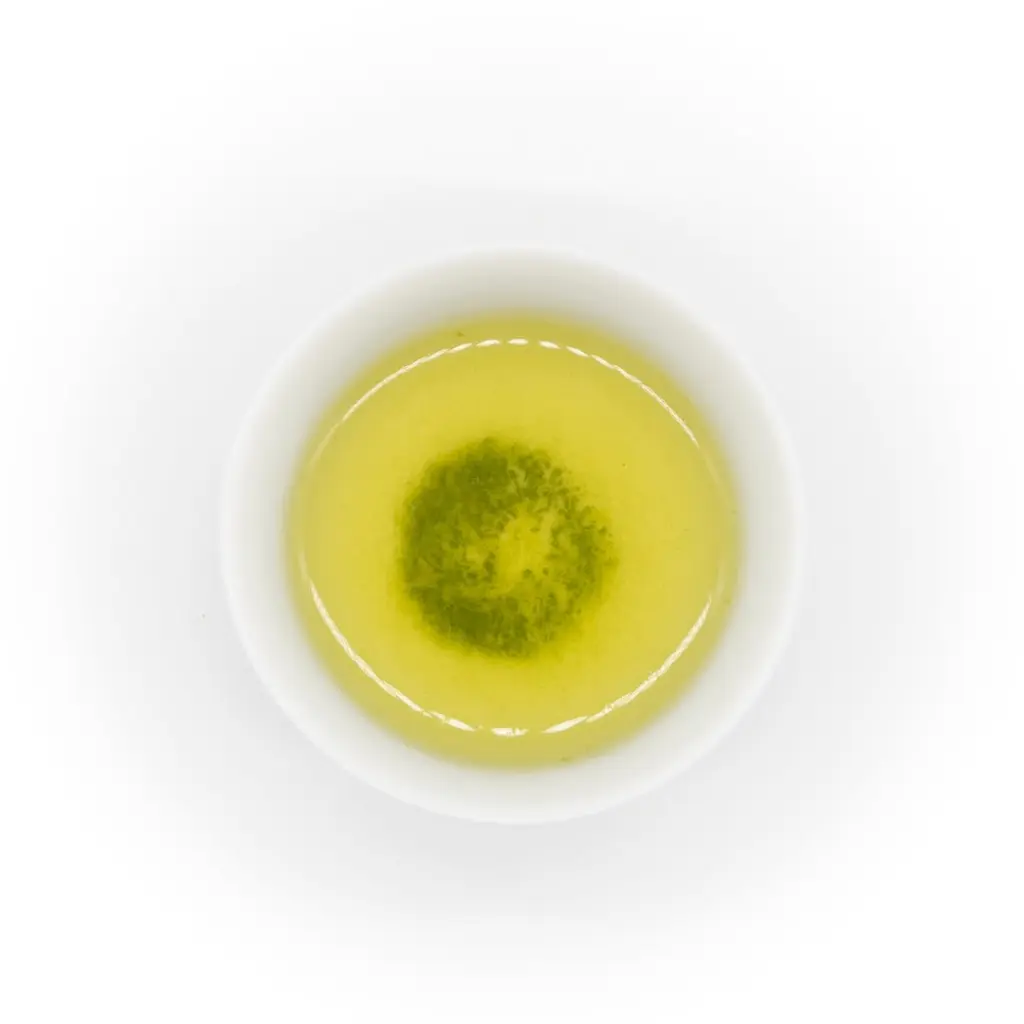 Top view of pale green tea with dark green sediment in a white cup