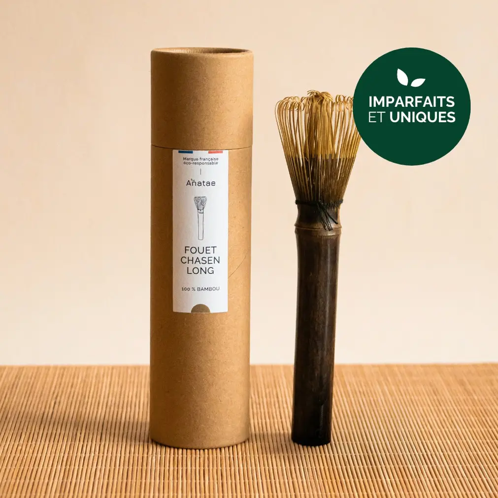 Long-handle bamboo matcha whisk beside Anatae cylindrical packaging