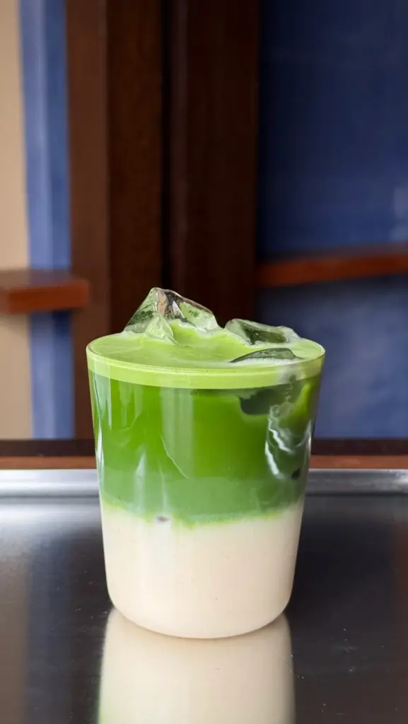 Layered green and cream-colored iced drink in a clear glass