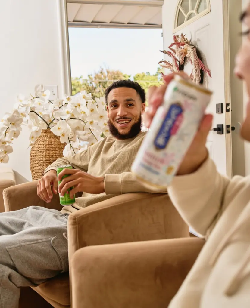 Two people seated indoors holding Ito En tea cans
