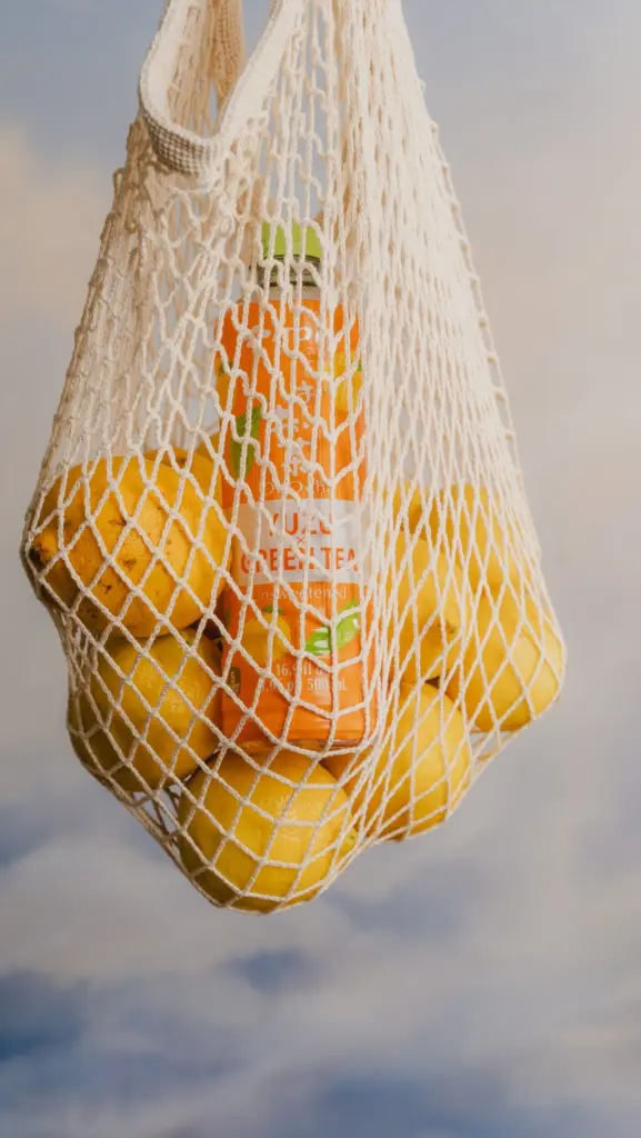 Ito En Yuzu Green Tea bottle and yellow citrus fruit in a hanging net bag