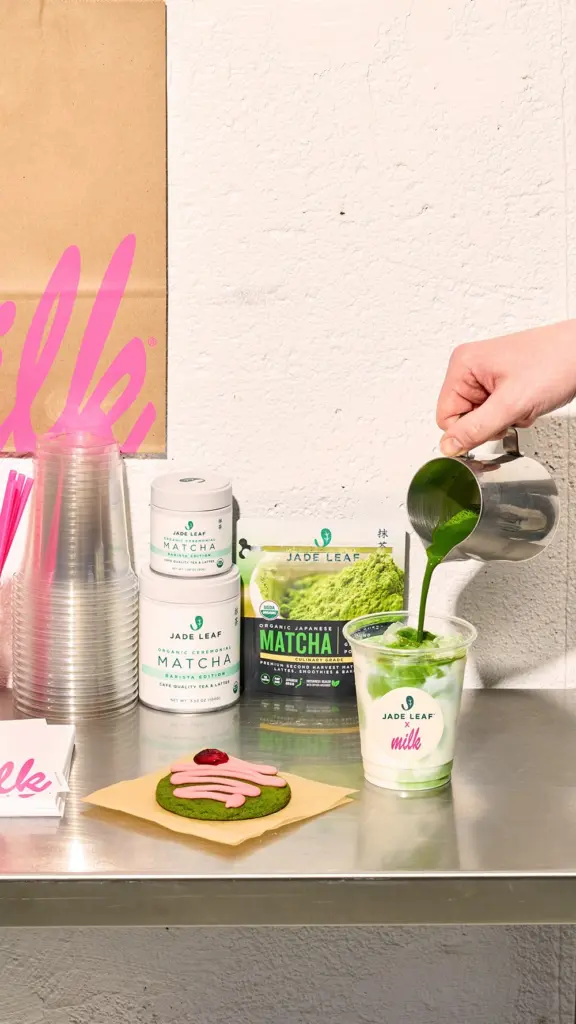 Green matcha poured into an iced milk drink beside a frosted green cookie