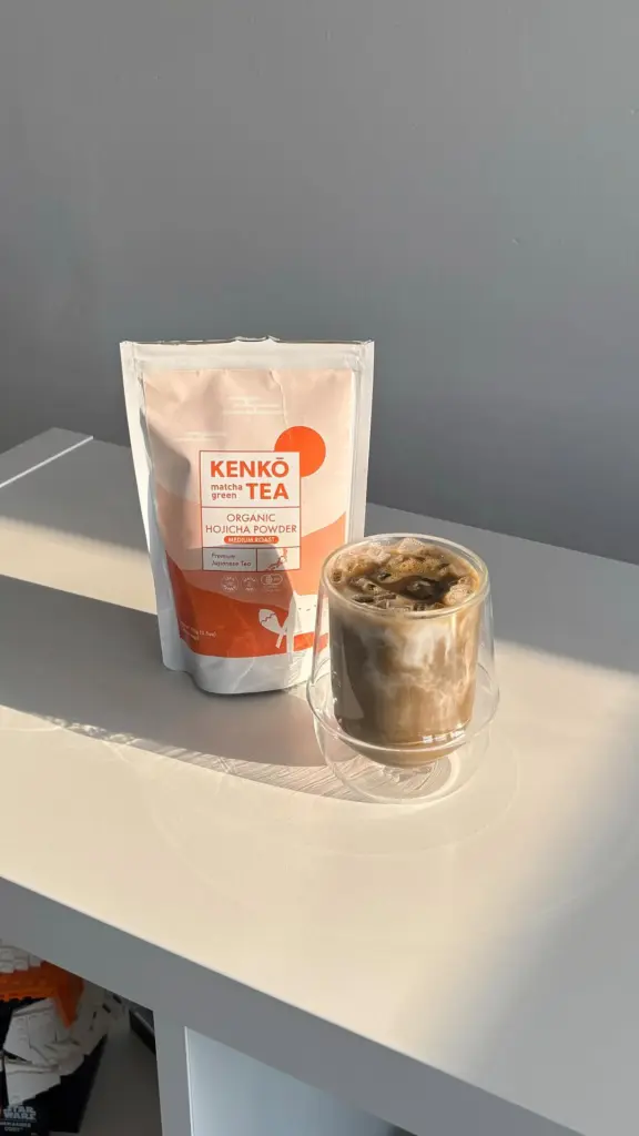 Iced creamy brown drink beside a Kenko Tea hojicha powder pouch