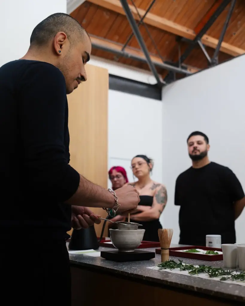 Presenter preparing tea while three people watch across a counter