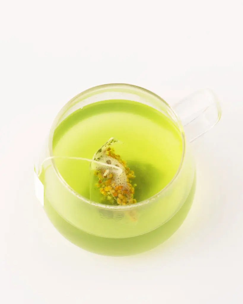 Bright green tea with a tea bag in a clear glass cup