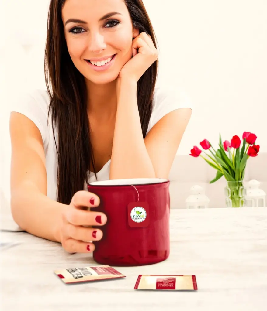 Smiling woman holding a red tea mug beside red tulips