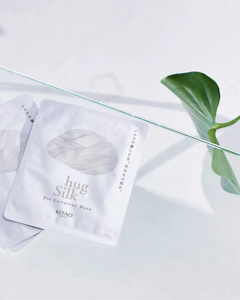 White Kitao Hug Silk mask packets beside a large green leaf
