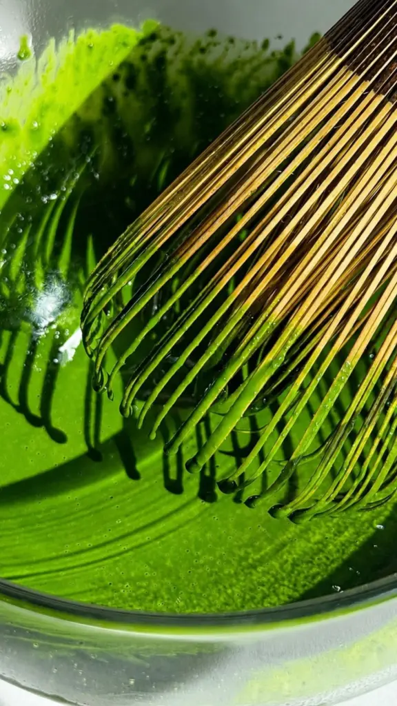 Bamboo whisk coated in bright green matcha