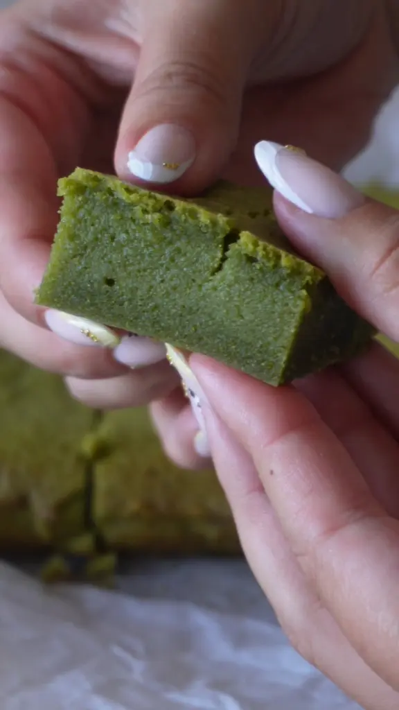 Hands breaking apart a dense green baked square