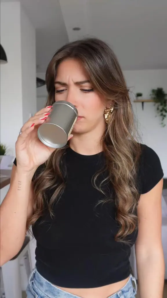 Woman tasting a drink from a gray metal cup
